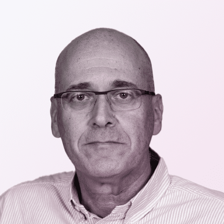 A middle-aged man with glasses and a bald head, wearing a light-colored collared shirt, facing forward against a plain light background.