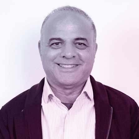 A middle-aged man with short gray hair is smiling at the camera, wearing a collared shirt and a zip-up jacket against a plain light background.