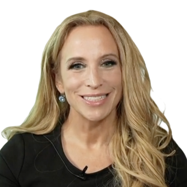 A woman with long blonde hair, wearing a black top and earrings, smiles at the camera against a plain white background, ready to discuss the evolving cybersecurity landscape.